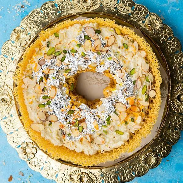 : Malai Ghevar (sweet honeycomb fritter) topped with rabdi, pistachios, and silver leaf.